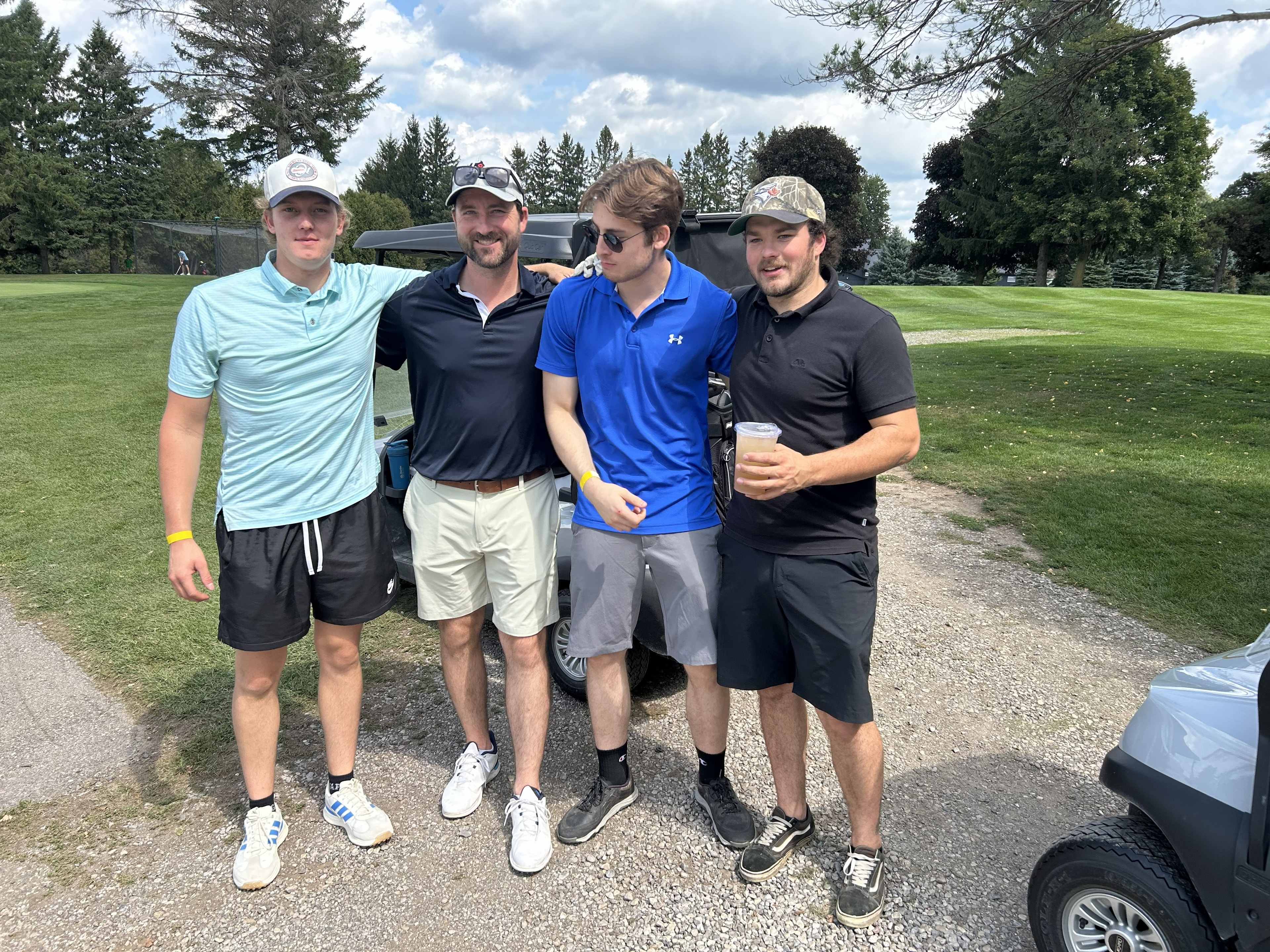 Team of four golfers posing by golf carts